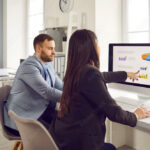 Business professionals analyze performance metrics on a data visualization screen, highlighting the role of analytics in modern corporate decision-making.