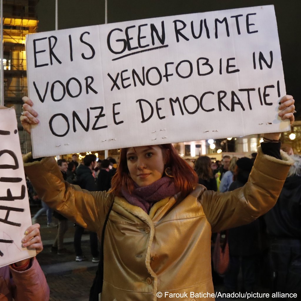A protester at a Dutch demonstration holds a sign rejecting xenophobia, highlighting public concern over the country's handling of asylum seekers.