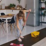 A cleaning worker in France, whose wages may be at risk due to subcontractor failures, performs her duties in a well-lit, tidy home environment.