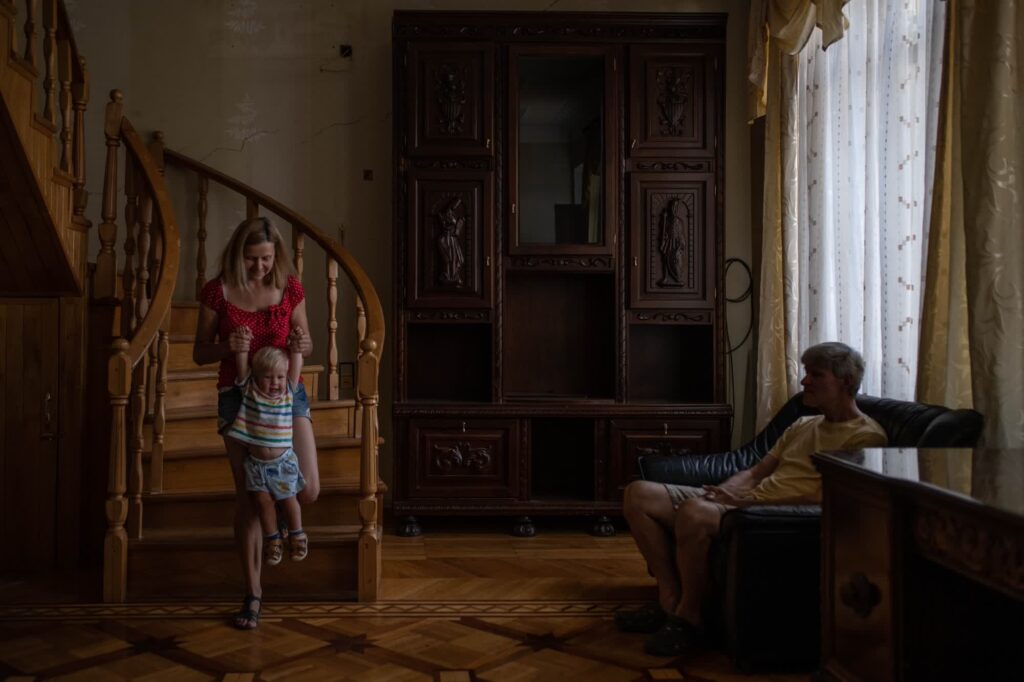 A Ukrainian family finds refuge in a warmly lit, traditionally furnished room, as the European Union grapples with the future of its migration policies.