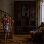 A Ukrainian family finds refuge in a warmly lit, traditionally furnished room, as the European Union grapples with the future of its migration policies.