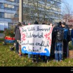 Protesters hold a banner demanding urgent climate action as Germany's top court blocks key climate measures, threatening EU green targets.