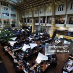 Traders work in a busy trading floor, reflecting the dynamic economic environment amid looming global uncertainties.