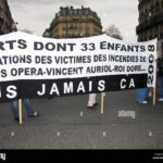 Protesters in Paris hold a banner demanding justice for victims of fires, highlighting the city's housing crisis and its parallels to the UK housing debate.